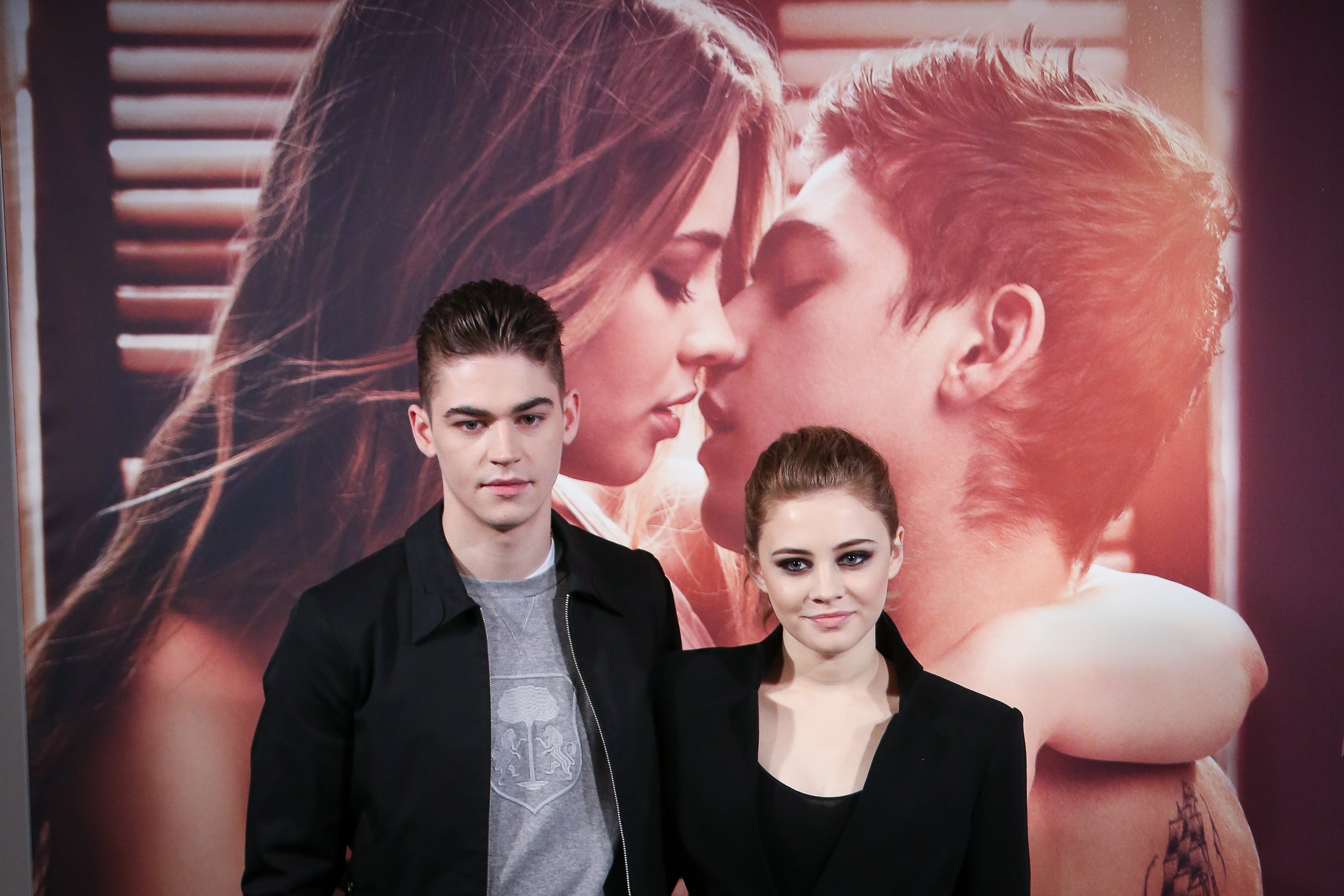 Josephine Langford and Hero Fiennes, stars of the After movies stand in front of a poster before they filmed After We Collided