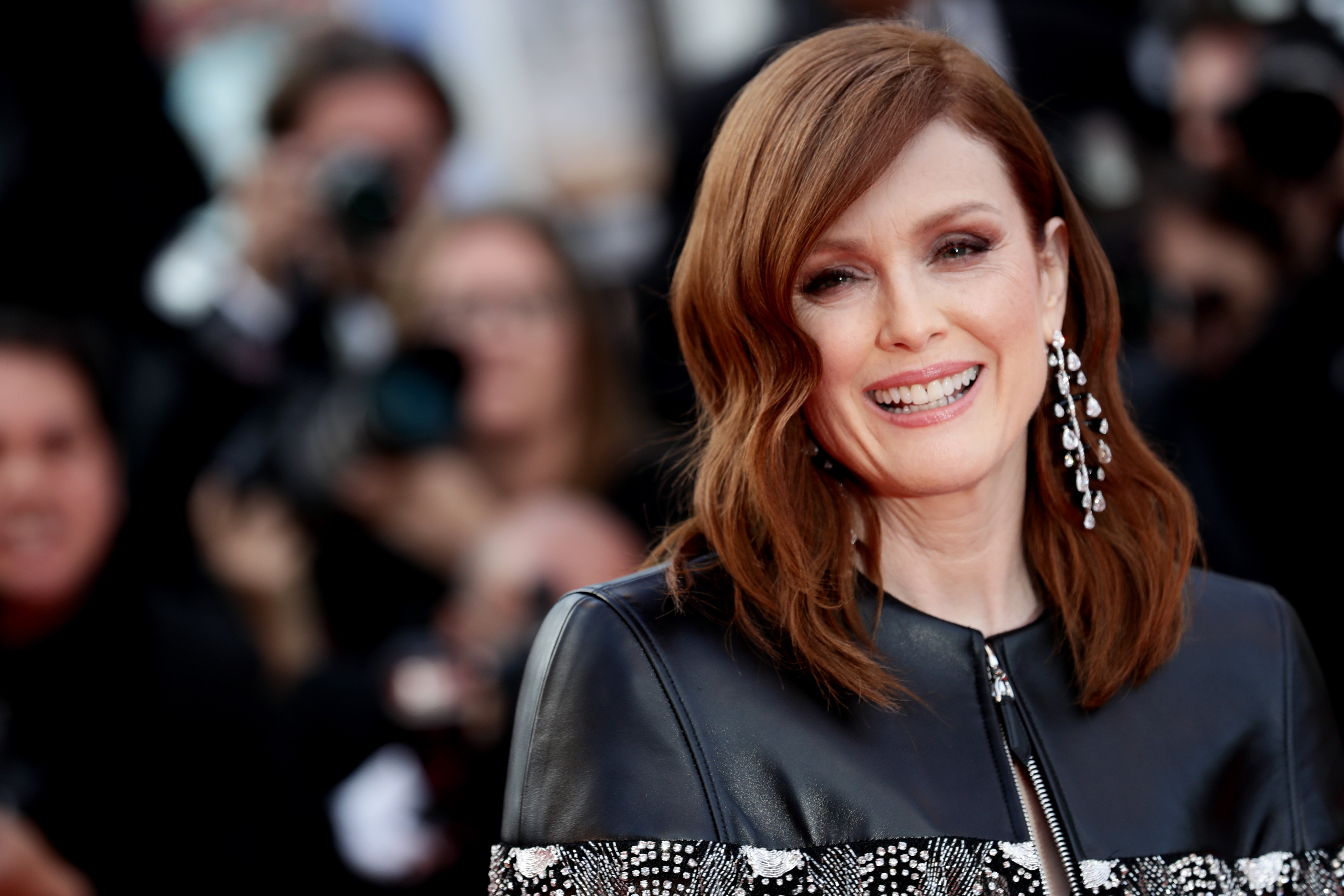 Julianne Moore star of Dear Evan Hansen smiles in front of red carpet cameras