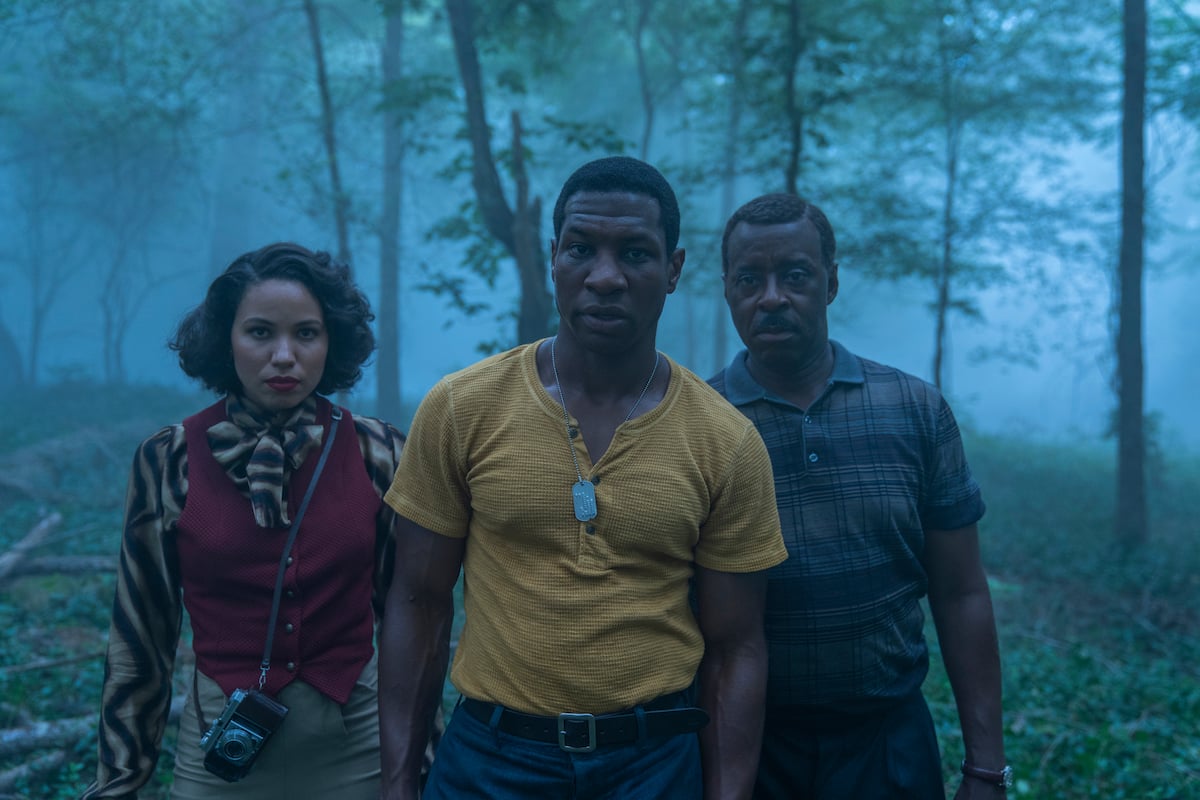 Jurnee Smollett, Jonathan Majors, and Courtney B. Vance standing in an open field in 'Lovecraft Country.'