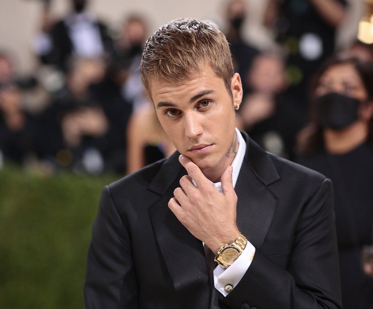 Justin Bieber poses in a black suit with one hand stroking his chin at the 2021 Met Gala.