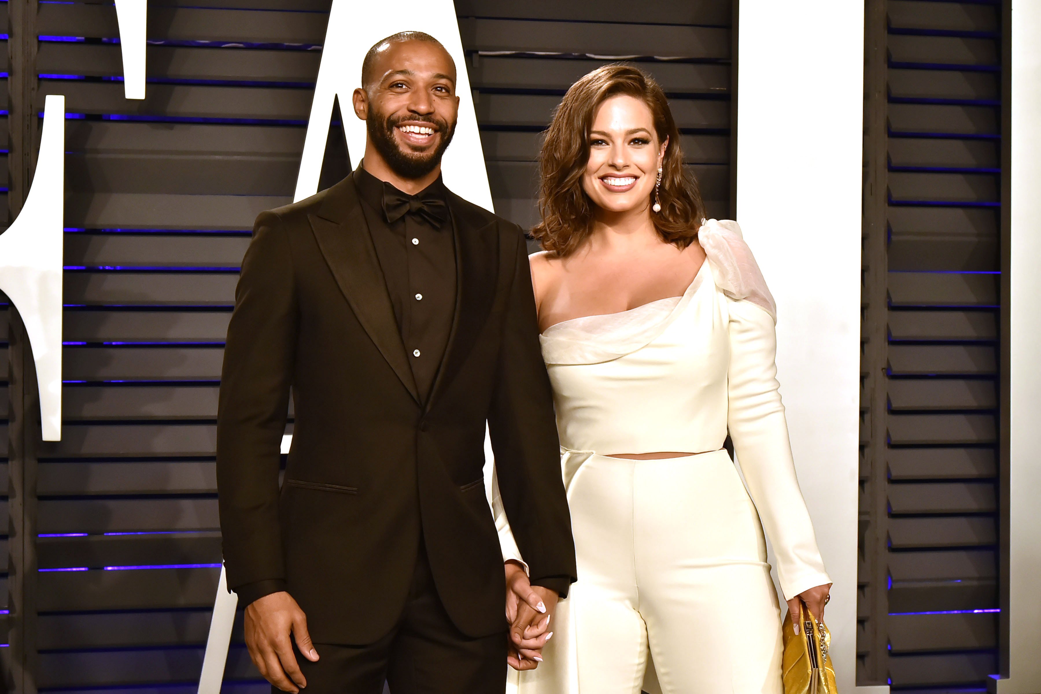 Justin Ervin in a black suit and Ashley Graham in a cream colored shirt and pants.