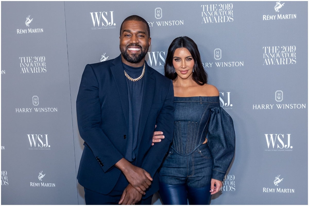 Kanye West and Kim Kardashian embracing each other and smiling on the red carpet.