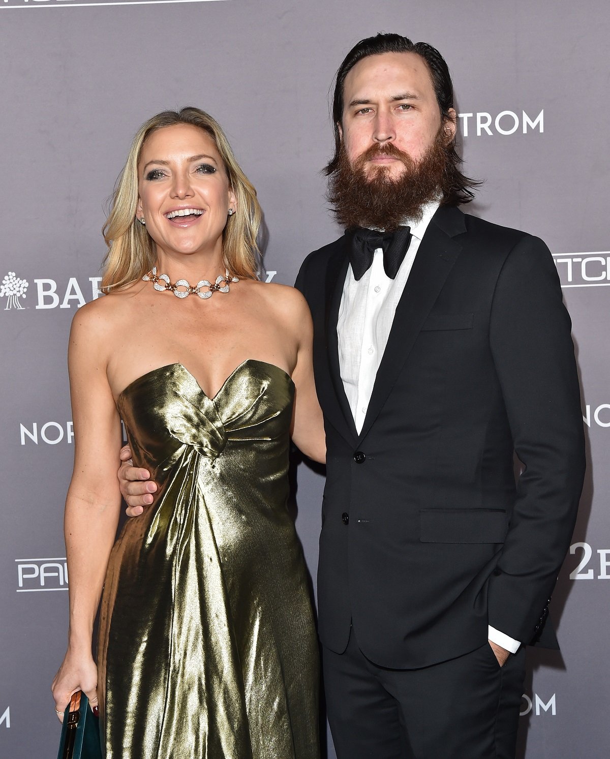Kate Hudson dons a shimmering gold gown while posing arm-in-arm Danny Fujikawa at the 2019 Baby2Baby Gala
