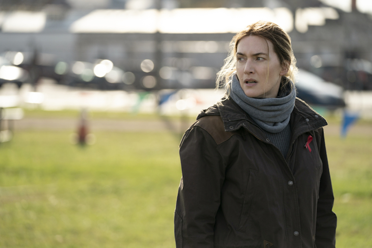 Kate Winslet in 'Mare of Easttown' looking off in the distance outdoors. Kate Winslet's net worth grew thanks to her role as a detective in the show.