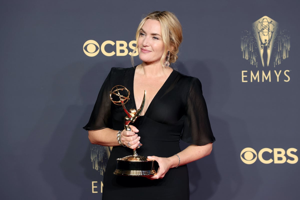 Kate Winslet holds her Emmy award in a black dress