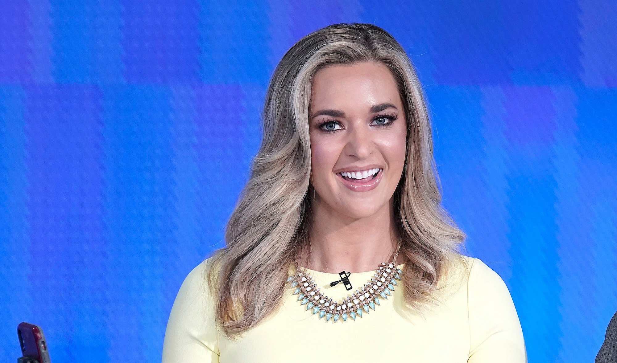 Katie Pavlich smiling in front of a blue background