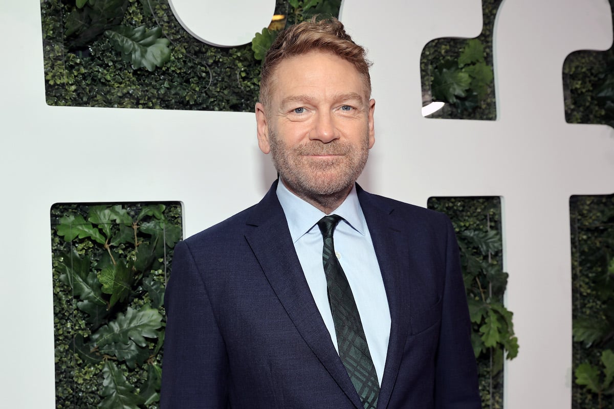 Kenneth Branagh attends the 'Belfast' premiere during the 2021 Toronto International Film Festival on Sept. 12, 2021. He wears a blue suit, light blue shirt, and green patterned tie while standing in front of a wall of foliage and 'TIFF' in big white letters. Branagh wrote and directed 'Belfast,' inspired by his childhood in Ireland. He was brought to tears by the positive audience reaction to his semi-autobiographical film.