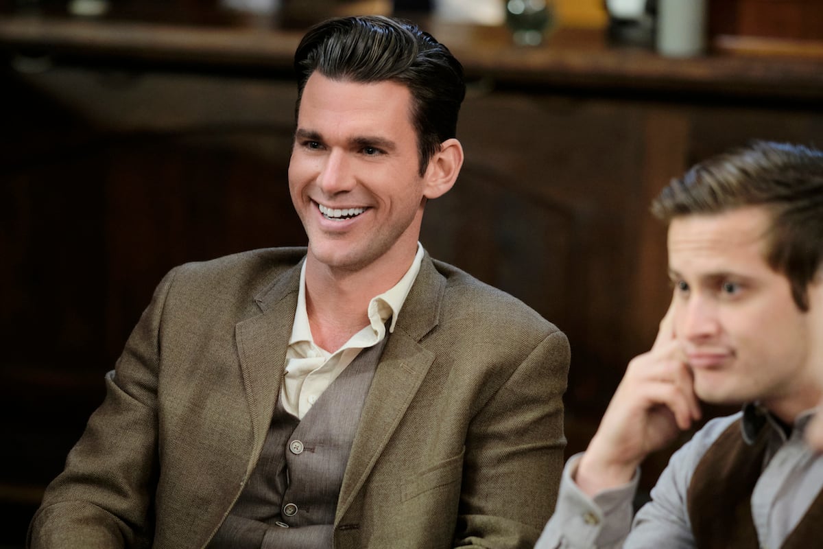Smiling Kevin McGarry as Nathan Grant sitting next to Aren Buchholz as Jesse in episode of 'When Calls the Heart' Season 8