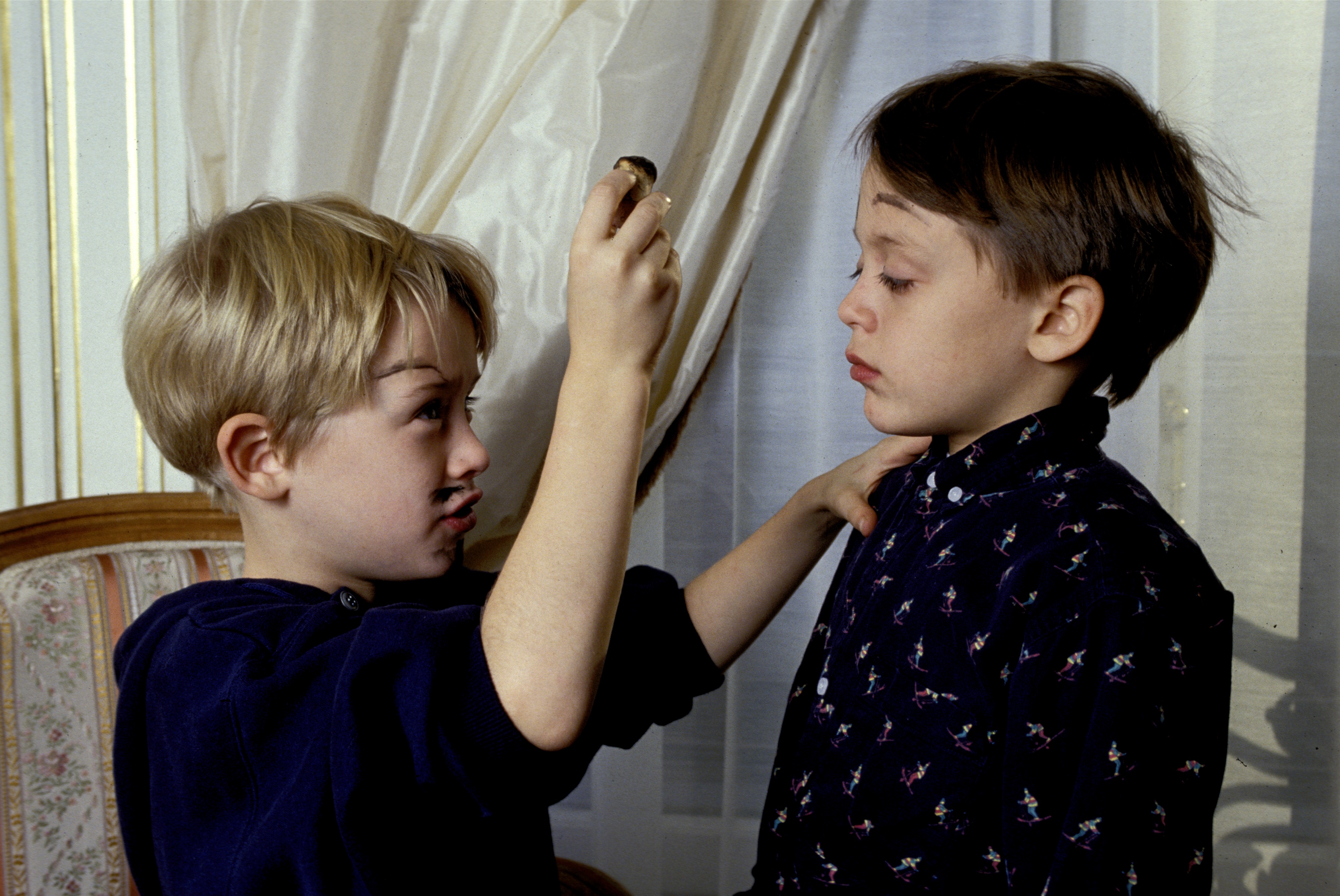 Macaulay Culkin paints Kieran Culkin's face with a wine cork in 1990.