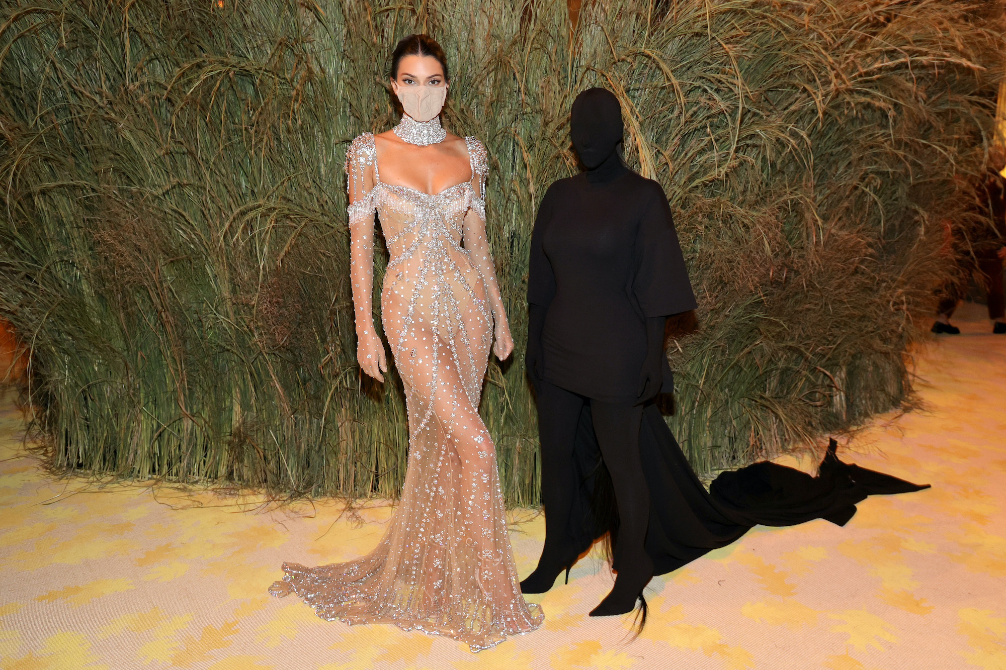 Kendall Jenner in a gown next to Kim Kardashian dressed in a full body t-shirt