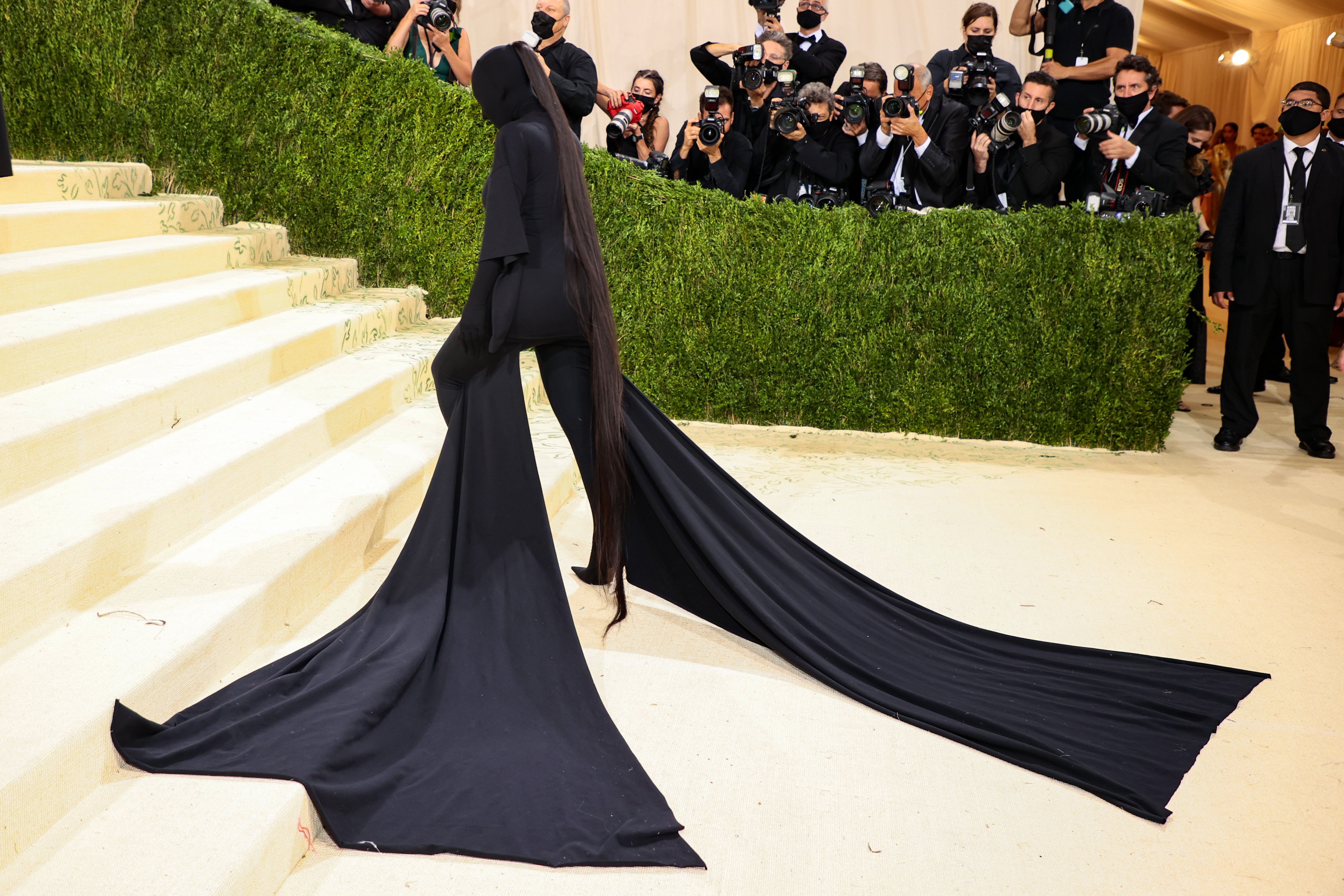 Kim Kardashian West climbs the Met steps in an all black outfit.