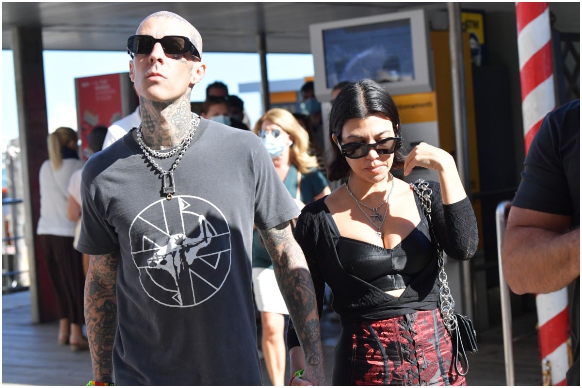 Kourtney Kardashian and Travis Barker walking outside in Venice wearing sunglasses and casual clothes.