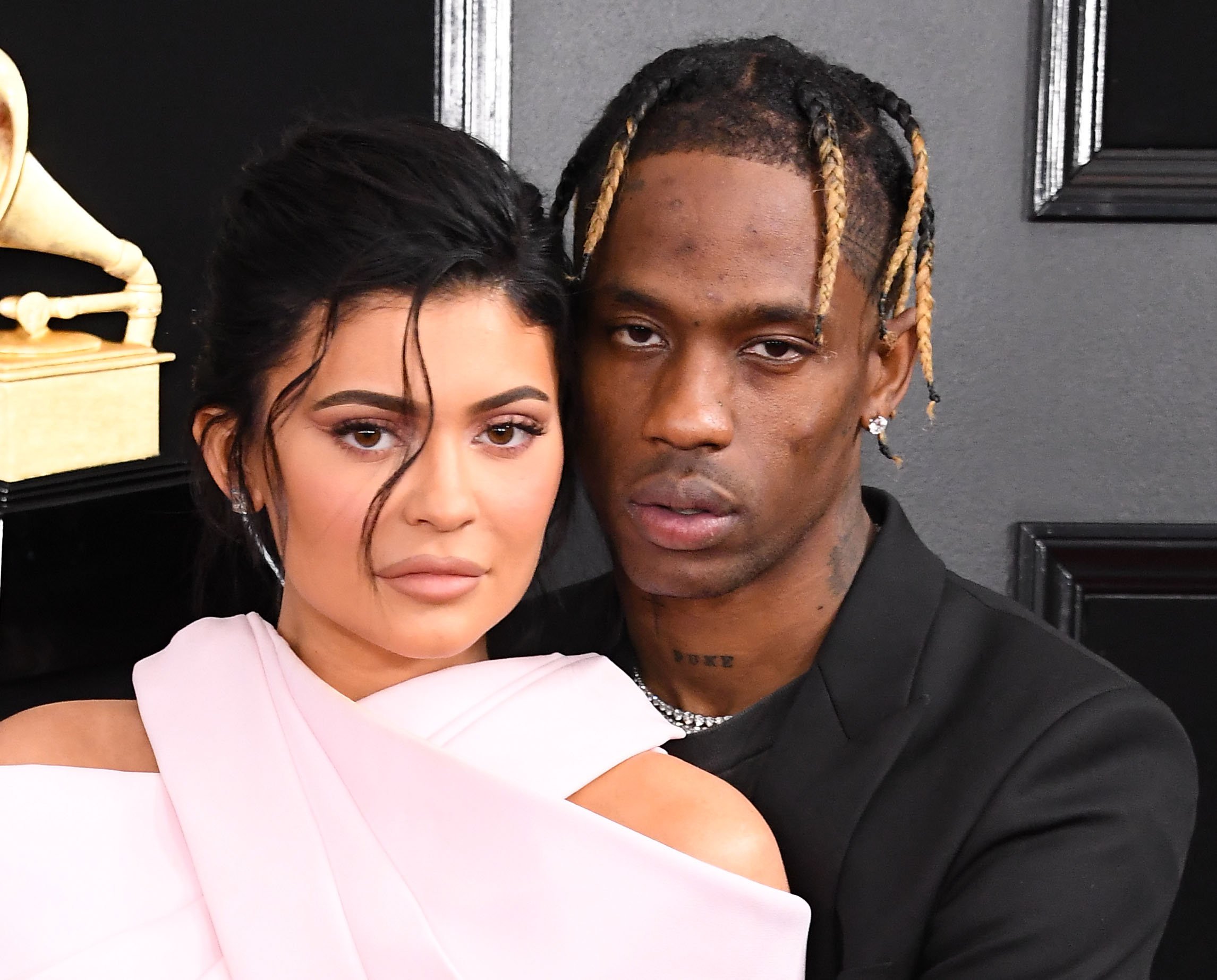 Kylie Jenner and Travis Scott looking intensely at the camera at the Grammy Awards.