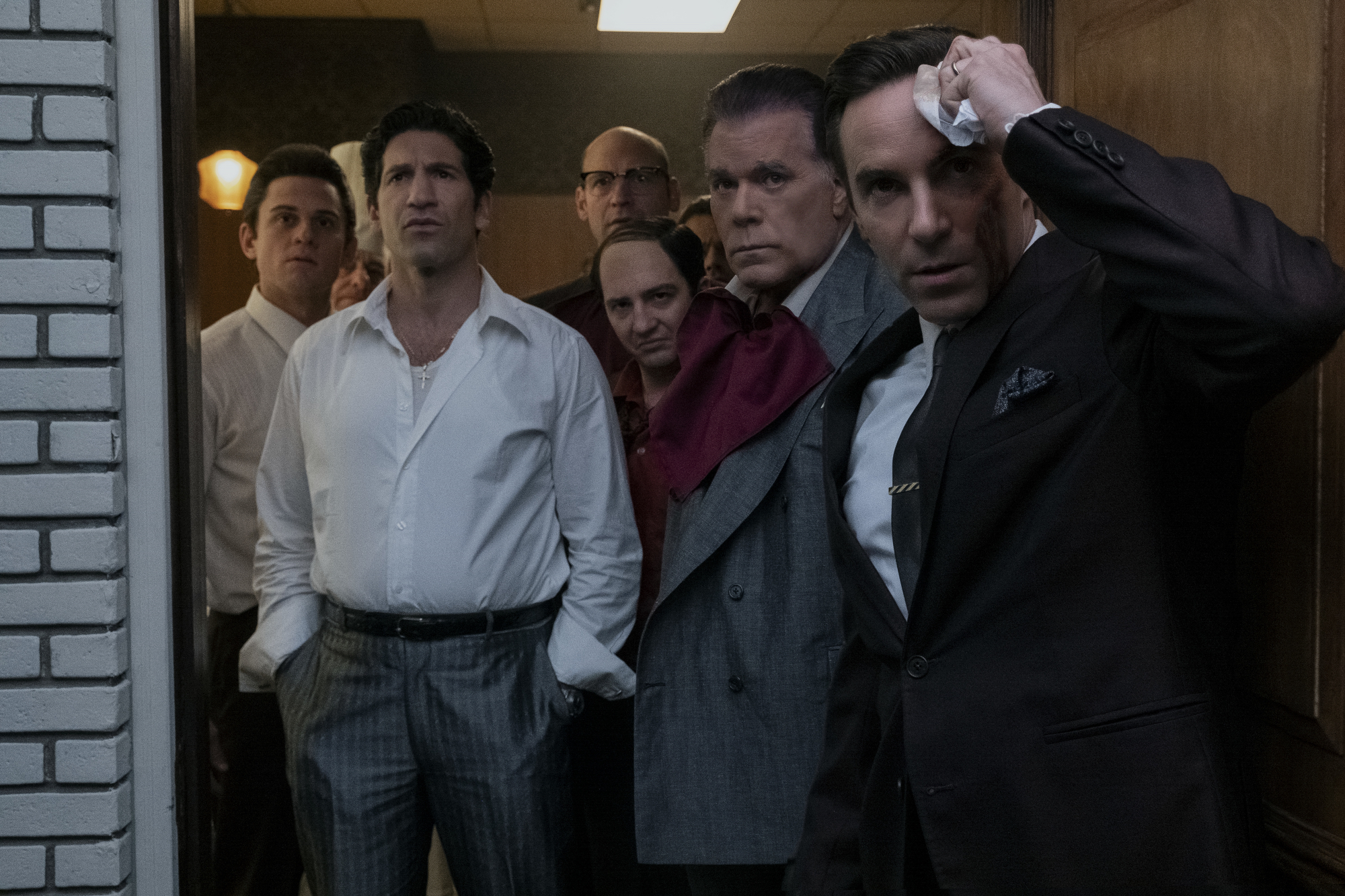 Billy Magnussen, Jon Bernthal, Corey Stoll, John Magaro, Ray Liotta, and Alessandro Nivola standing at window to observe the Newark riots