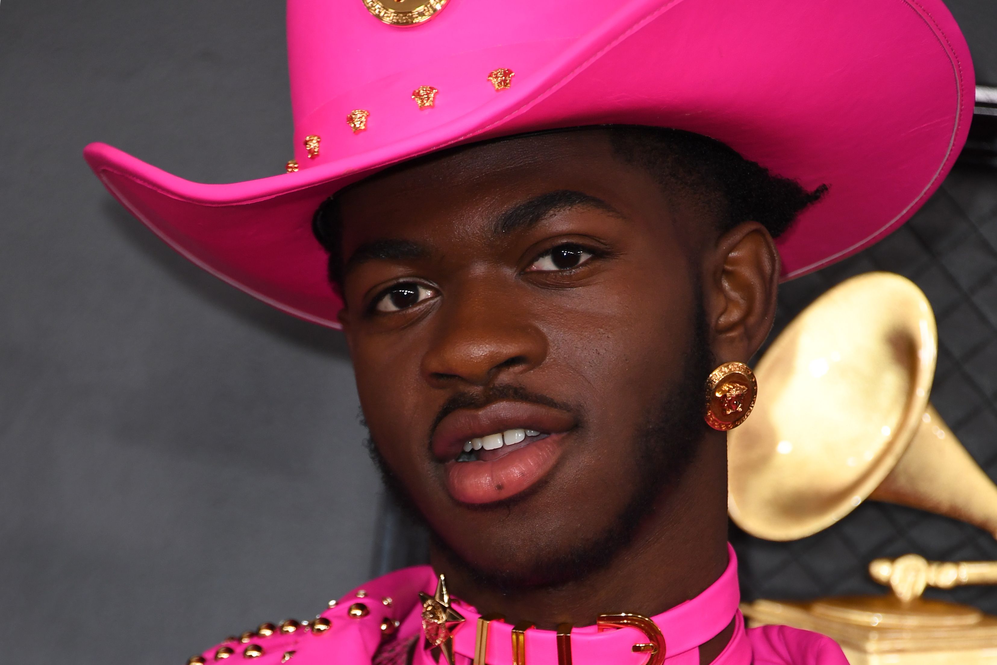 Lil Nas X wearing a pink hat poses for photographers.