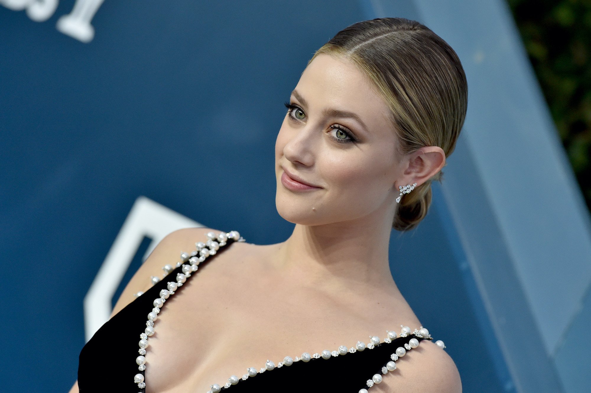 Lili Reinhart smiling in front of a blue background