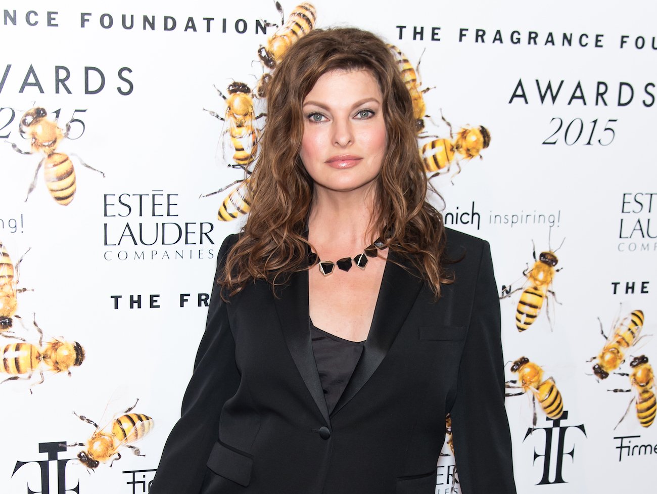 Linda Evangelista wearing a black outfit in front of a white background