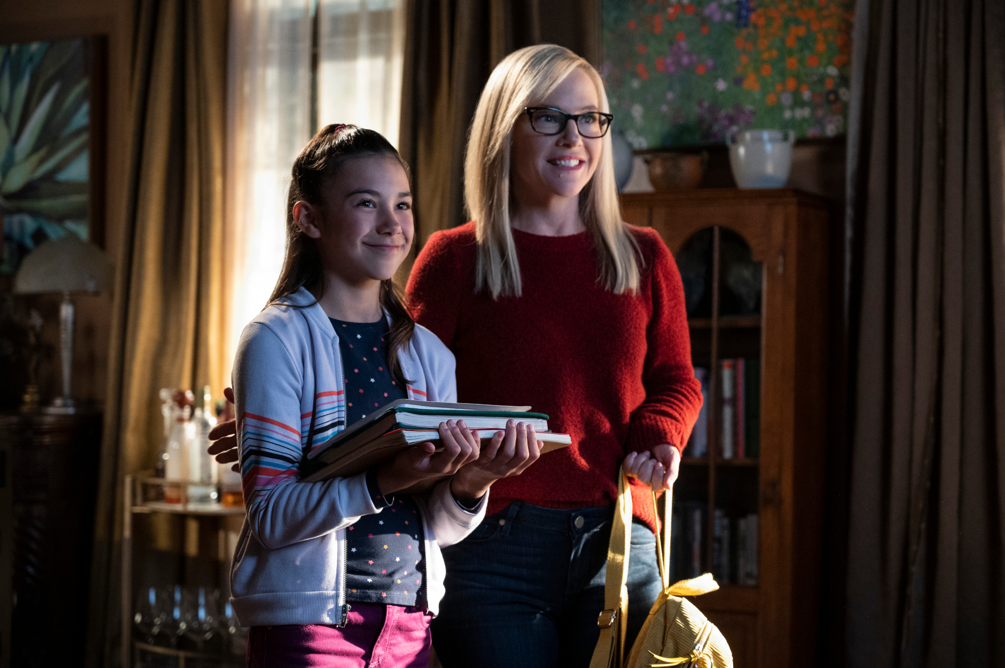 Scarlett Estevez and Rachael Harris as Trixie and Linda in 'Lucifer' Season 5, which built to the characters' endings in season 6. Trixie is holding a stack of books, and Linda is standing next to her in a red sweater.
