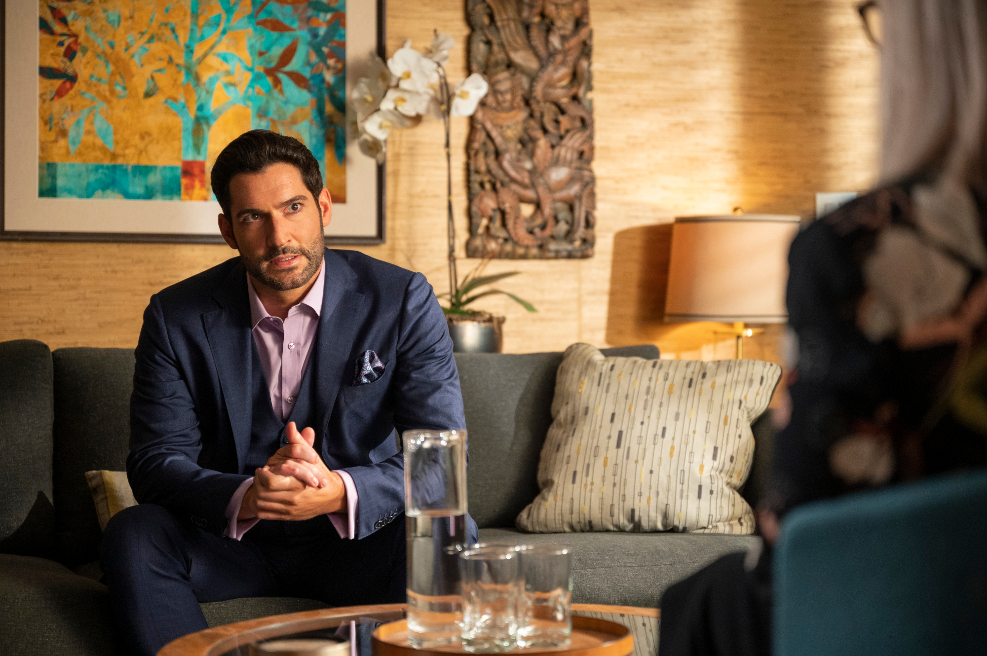 Tom Ellis as Lucifer Morningstar in 'Lucifer' Season 6. He's sitting on Linda's couch and venting.