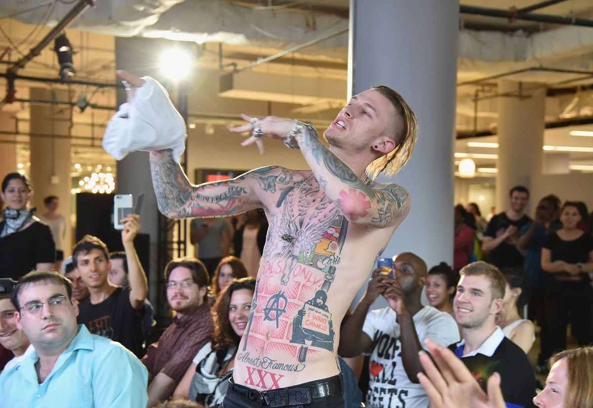 Machine Gun Kelly's tattoos are visible as her performs shirtless.