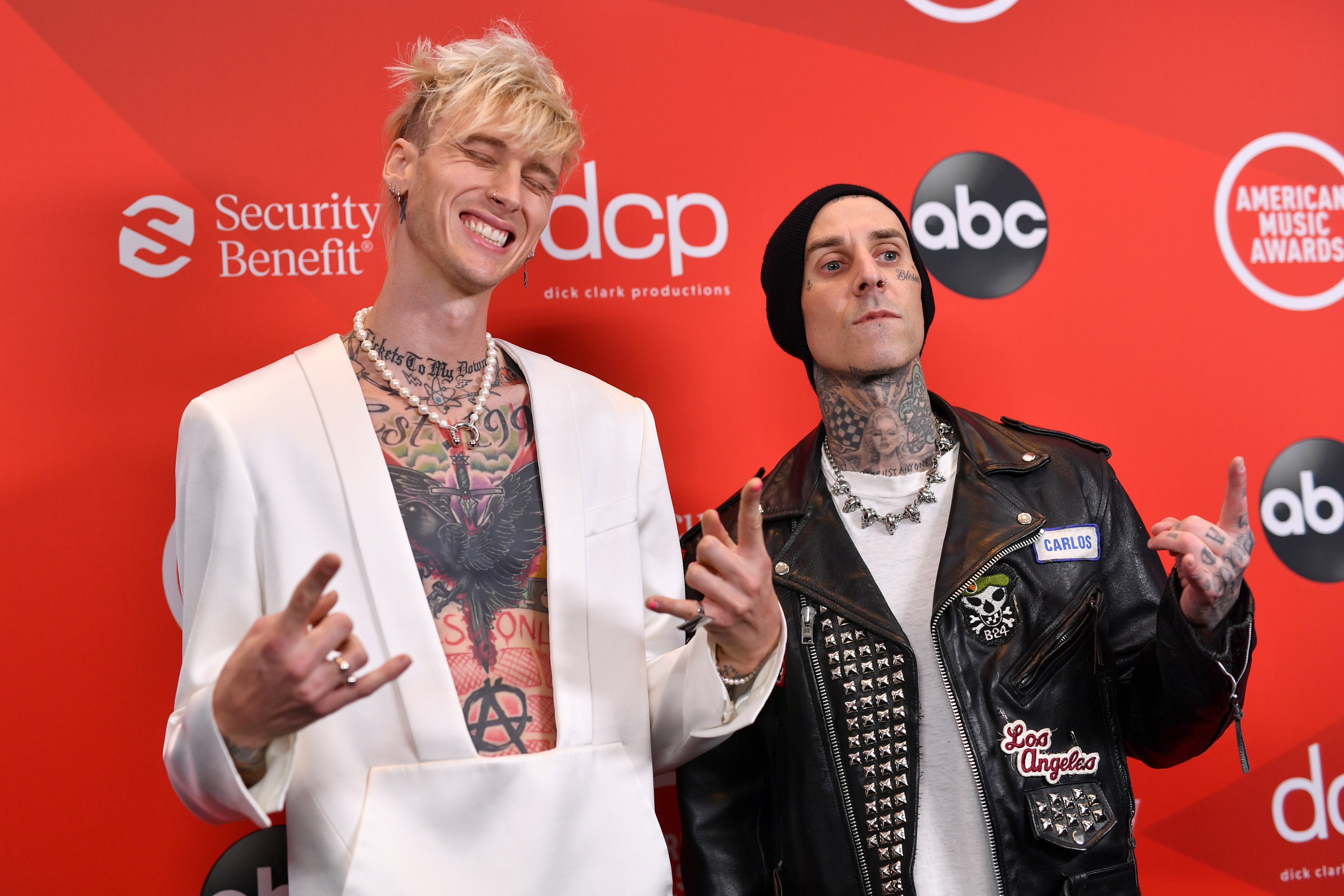Machine Gun Kelly in a white suit and Travis Barker in a black jacket.