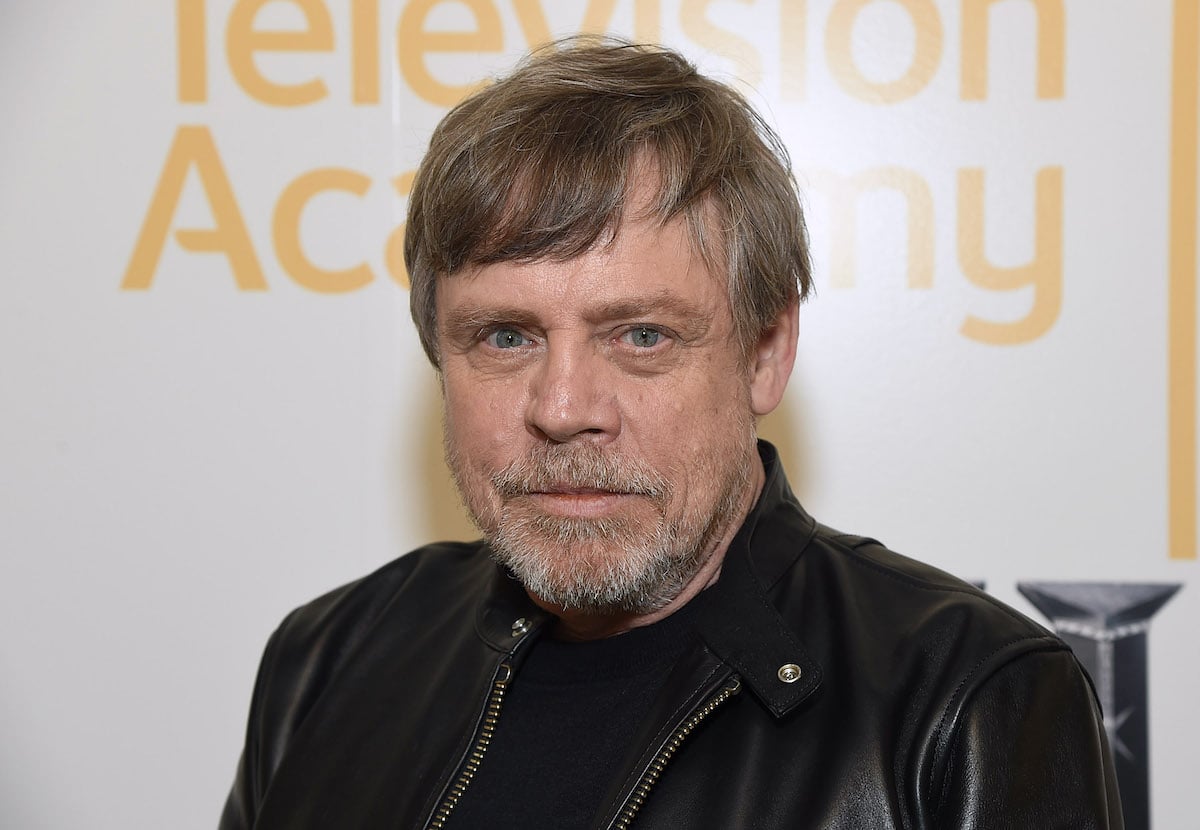 Mark Hamill smiling in front of a white background