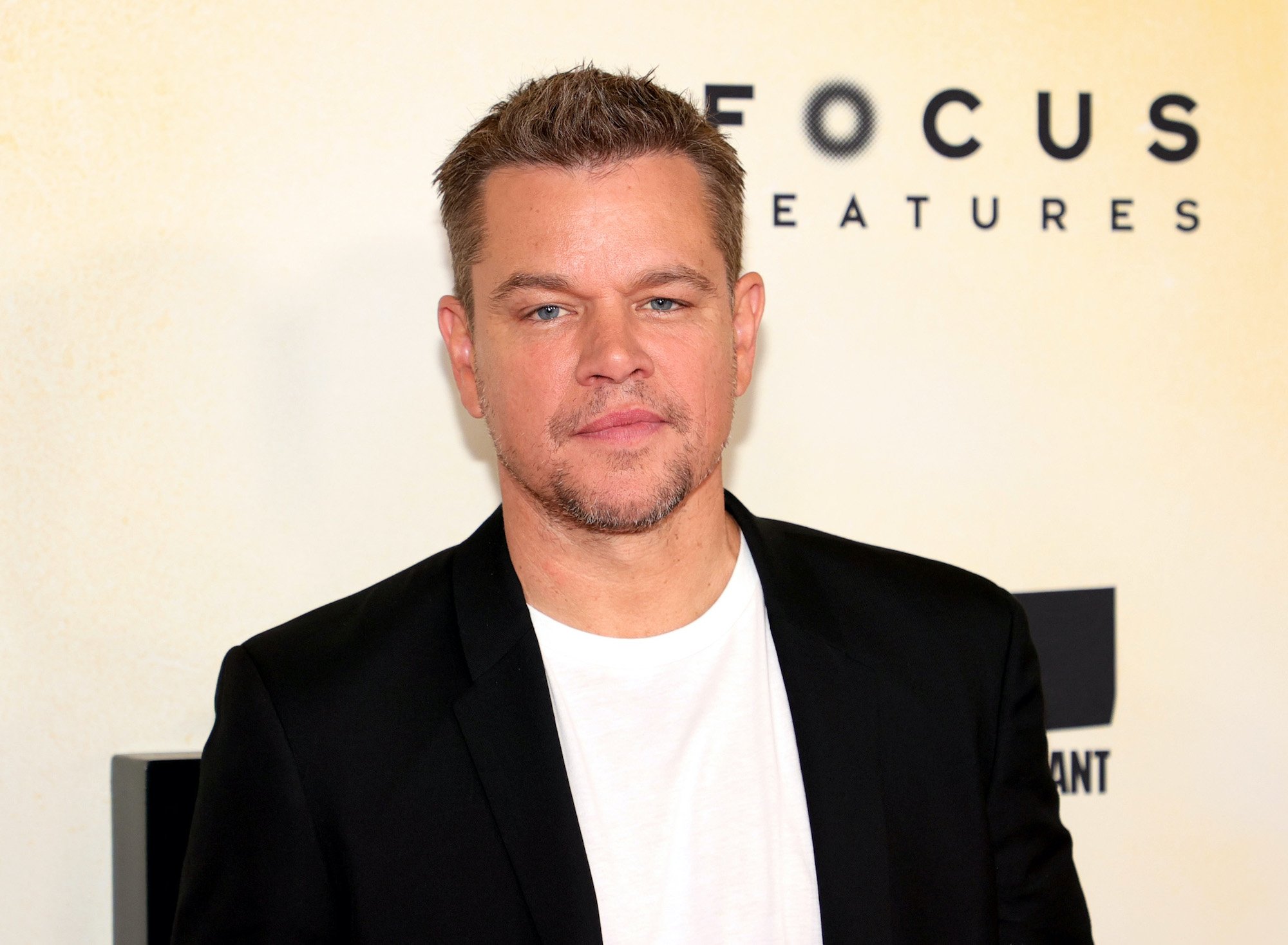 Matt Damon smiling in front of a beige background