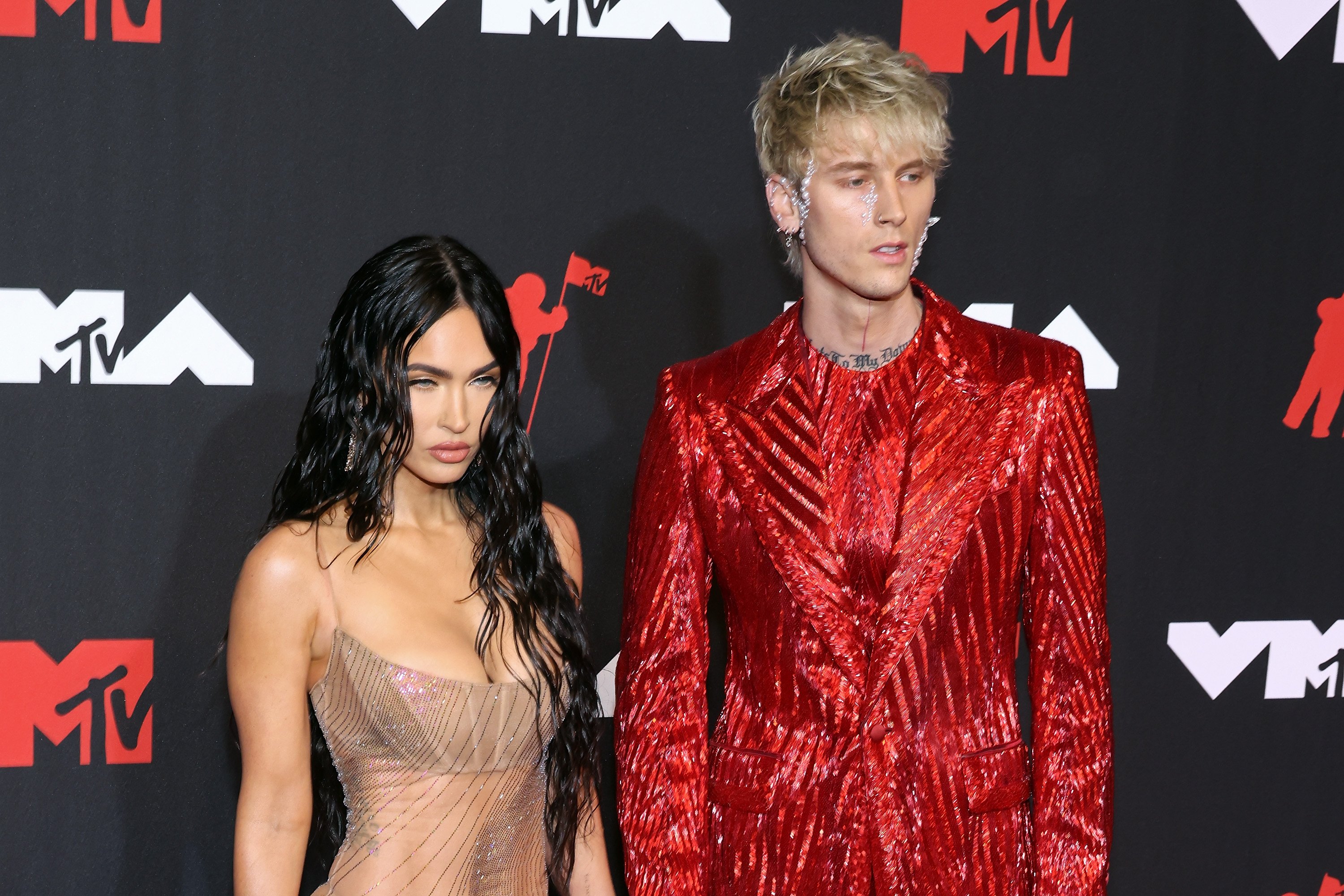 Megan Fox in a sheer dress and Machine Gun Kelly in a red suit at the VMAs.