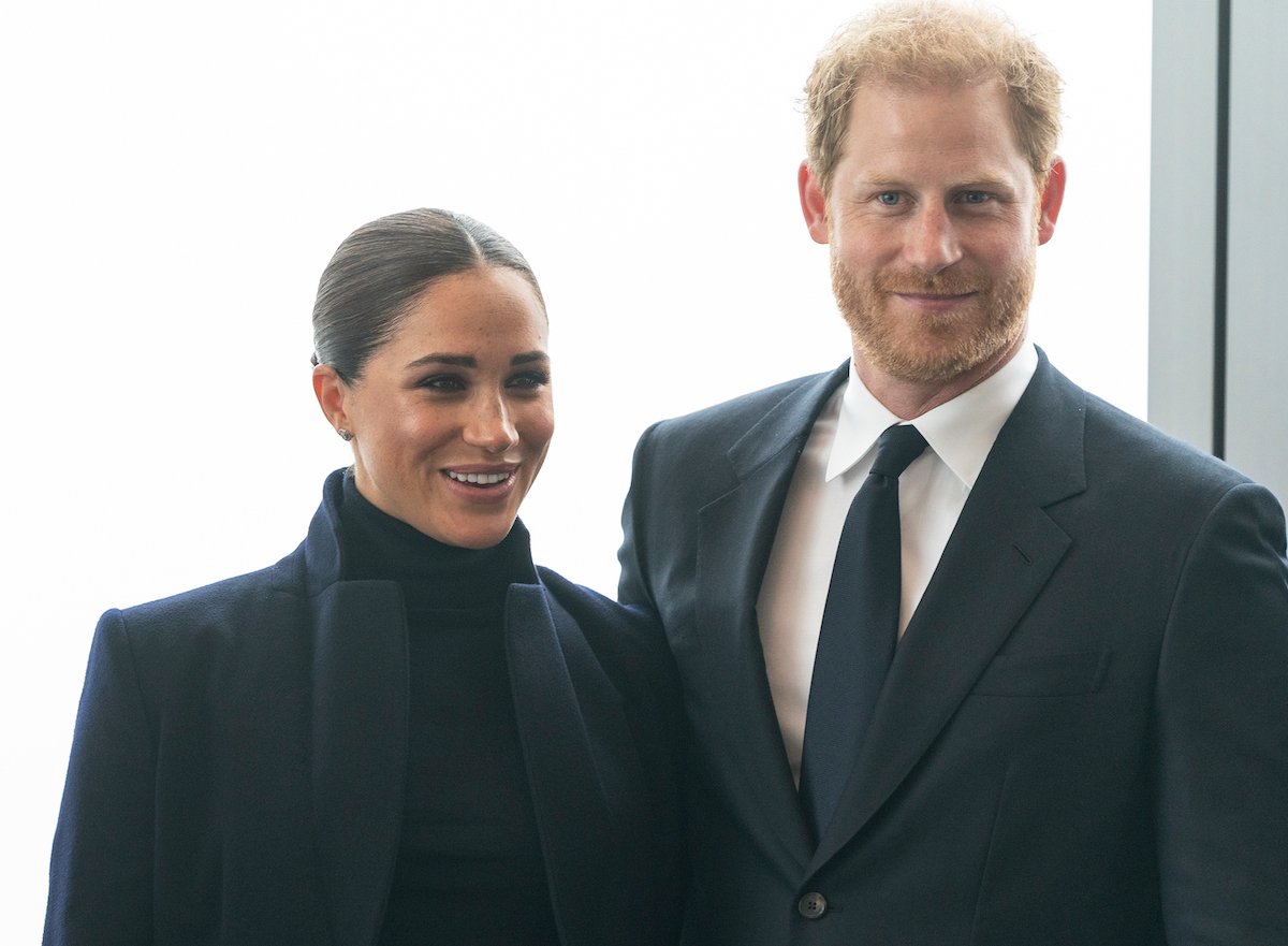 Meghan Markle wears a black turtleneck and jacket and Prince Harry wears a suit as they smile at One World Observatory in September 2021