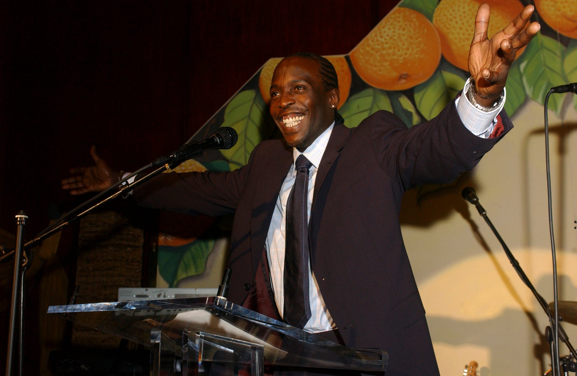 Michael K. Williams, the actor playing Omar on 'The Wire,' smiling with his hands outstretched at a podium
