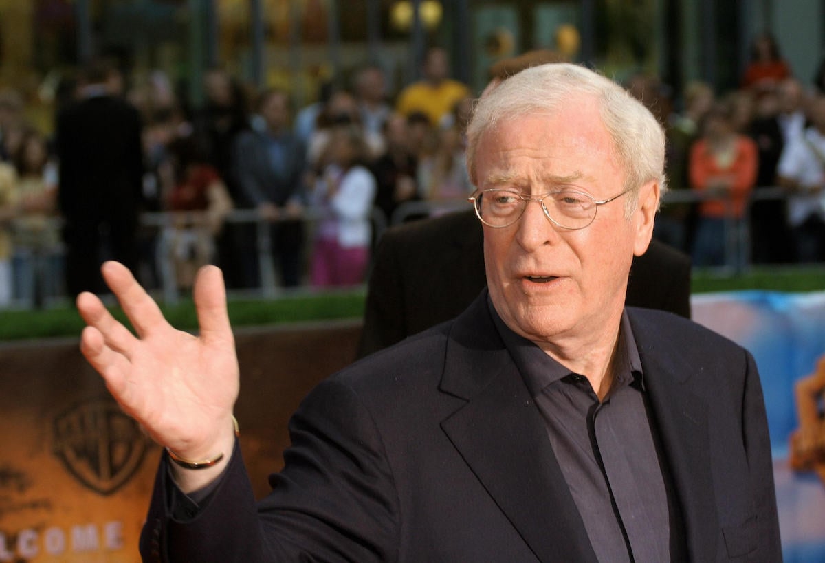 Michael Caine waving in black suit