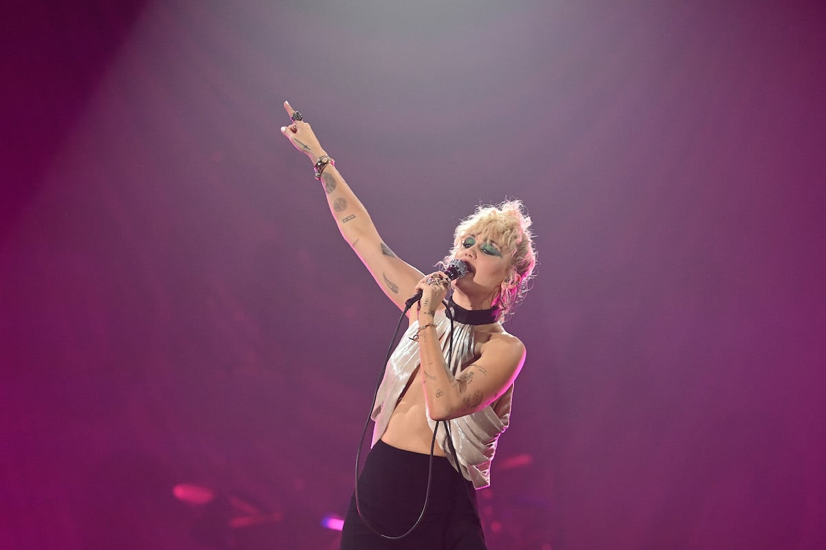 Miley Cyrus performing on stage in a white top.