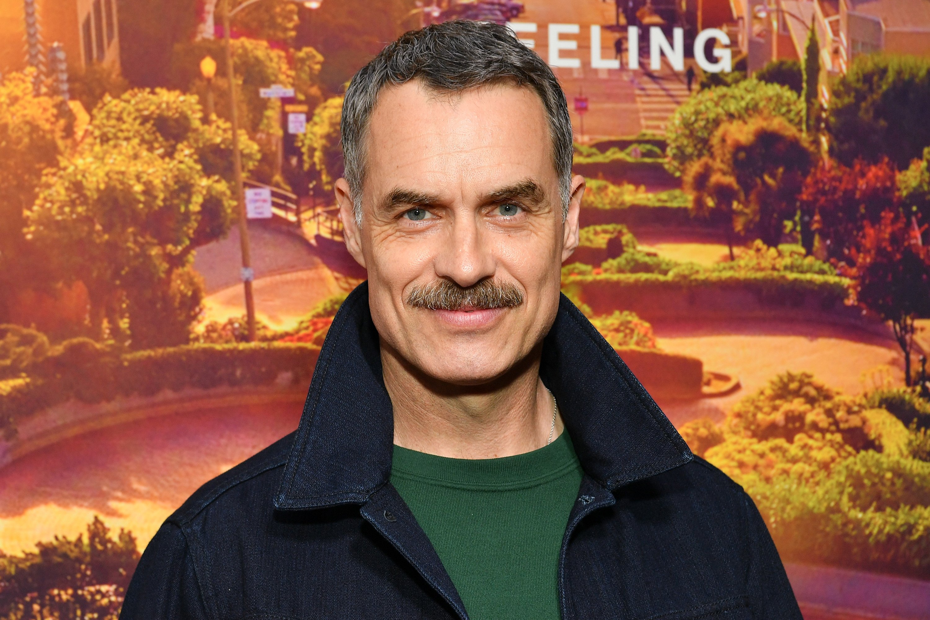 Murray Bartlett in a green shirt and black jacket.