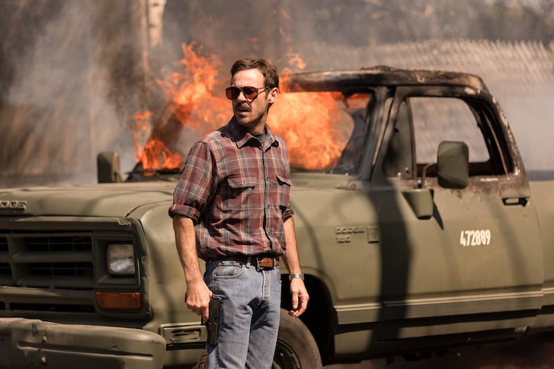 Scoot McNairy as Walt Breslin stands in front of a truck in flames.