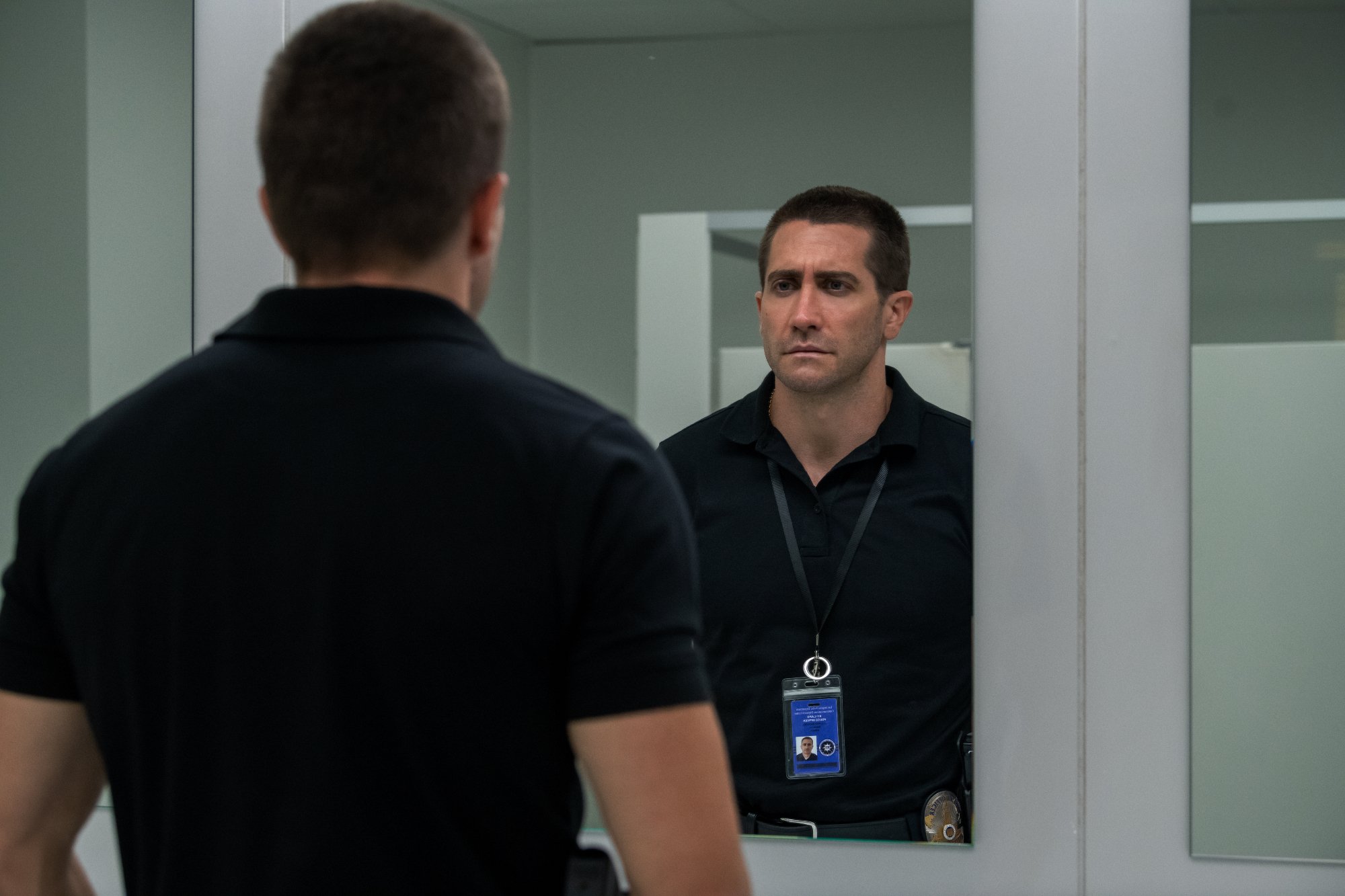 Netflix's 'The Guilty' star Jake Gyllenhaal as Joe Bayler looking in the mirror with his badge on