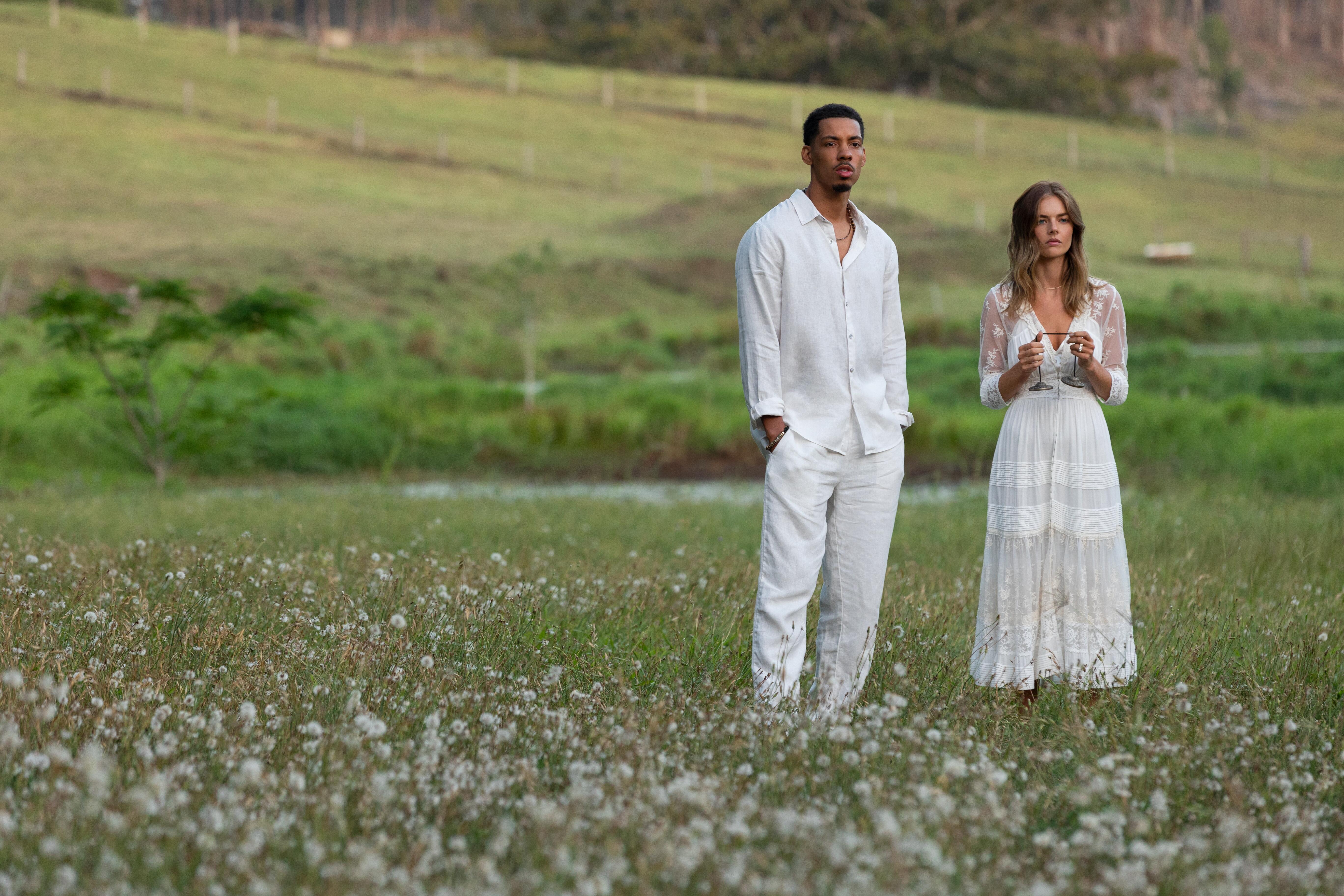 Ben and Jessica stand in a grassy field at Tranquillum House wearing all white in the 'Nine Perfect Strangers' finale.