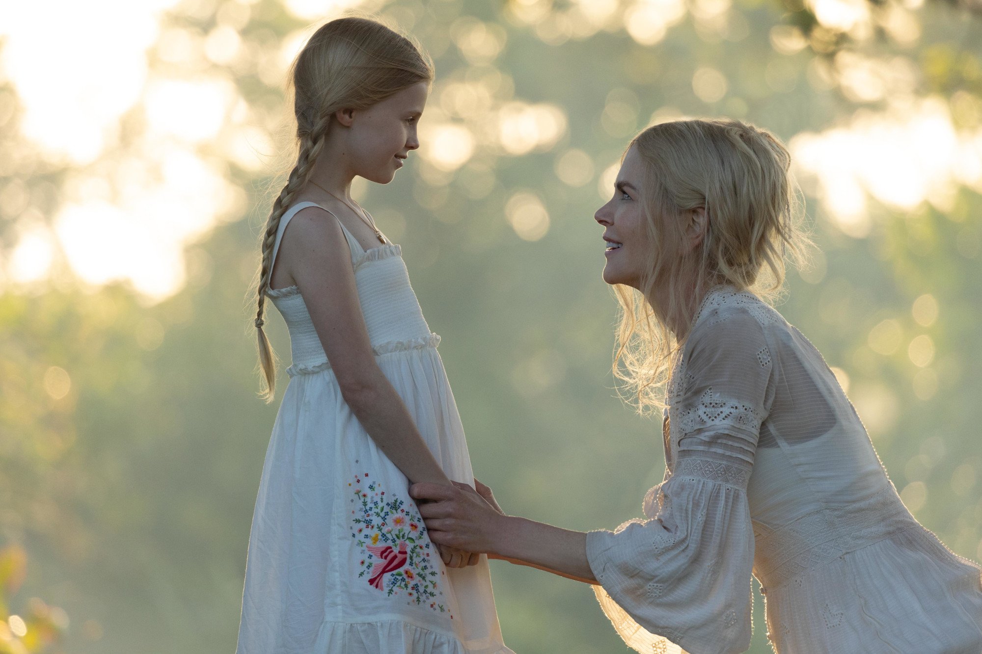 Masha (Nicole Kidman) reunites with her young daughter in the 'Nine Perfect Strangers' finale. She kneels in front of the young, blonde girl and there are trees and sunlight behind them.