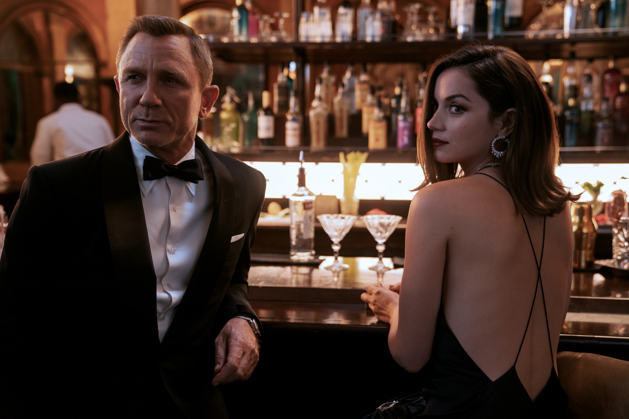 'No Time to Die' Imax movie stars Daniel Craig as James Bond and Ana de Armas as Paloma dressed in a suit and dress at the bar