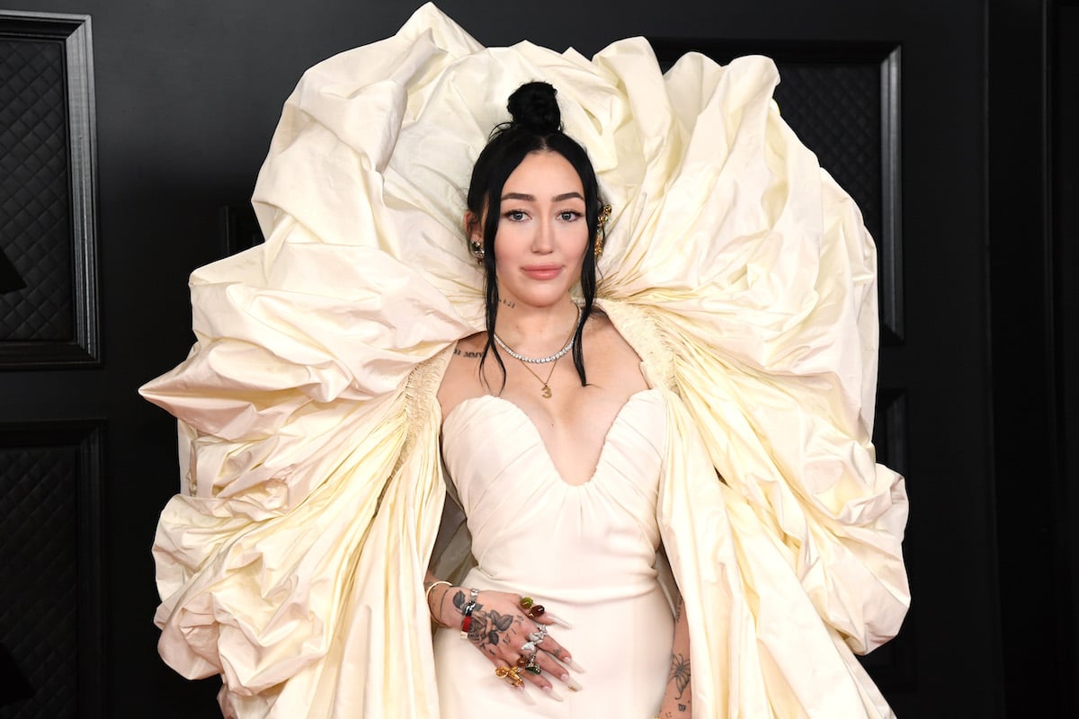 Noah Cyrus poses in a voluminous white gown at an event.