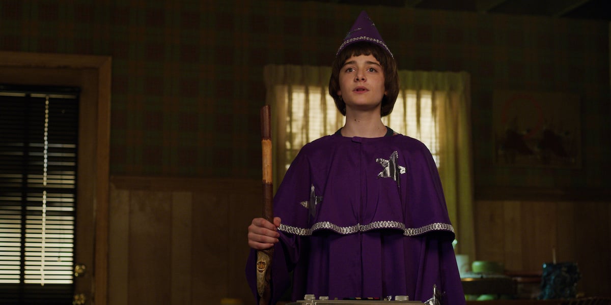 Will Byers (Noah Schnapp) dressed as Will the Wise in a purple wizard's robe and hat in a production still from 'Stranger Things' Season 3.