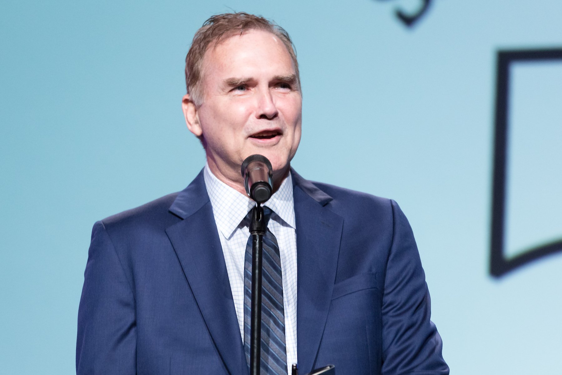 Comedian Norm Macdonald talking into a microphone