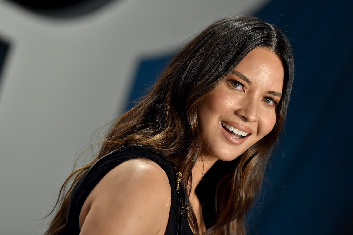 Olivia Munn looks over her shoulder to smile at the camera.