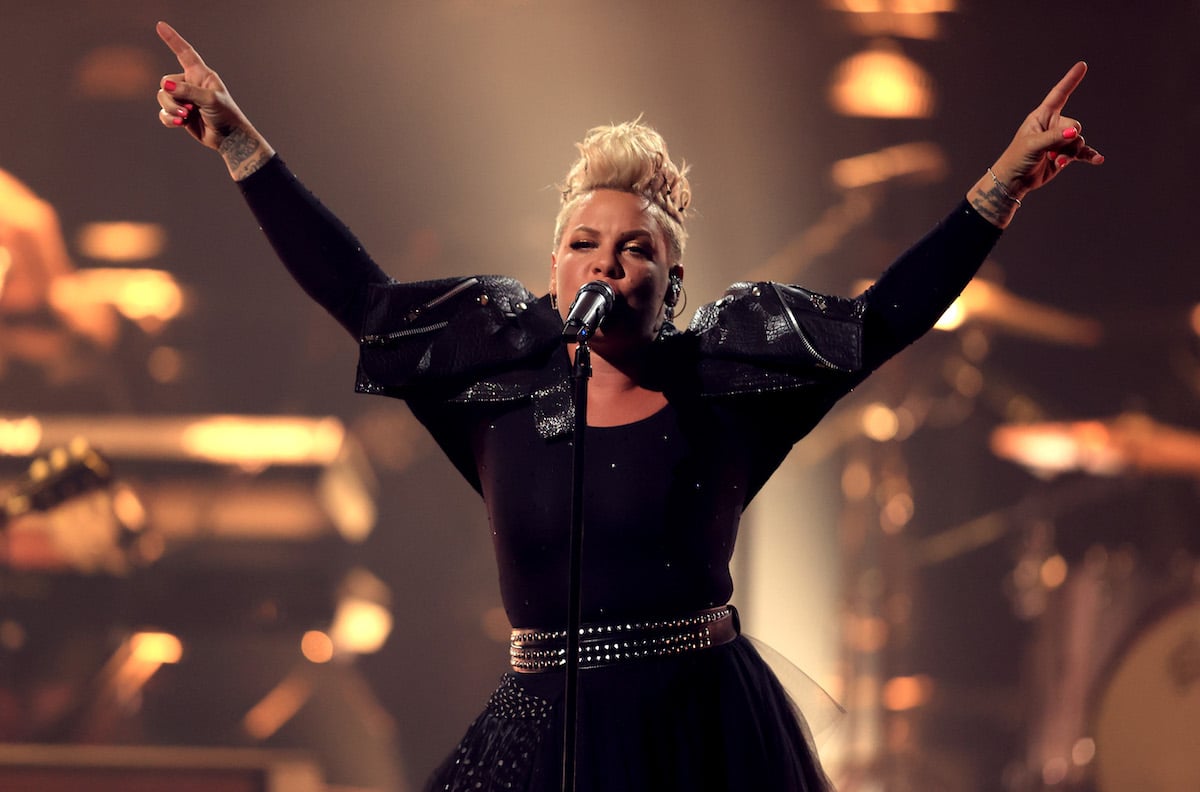 Pink performing on stage in an all-black outfit.