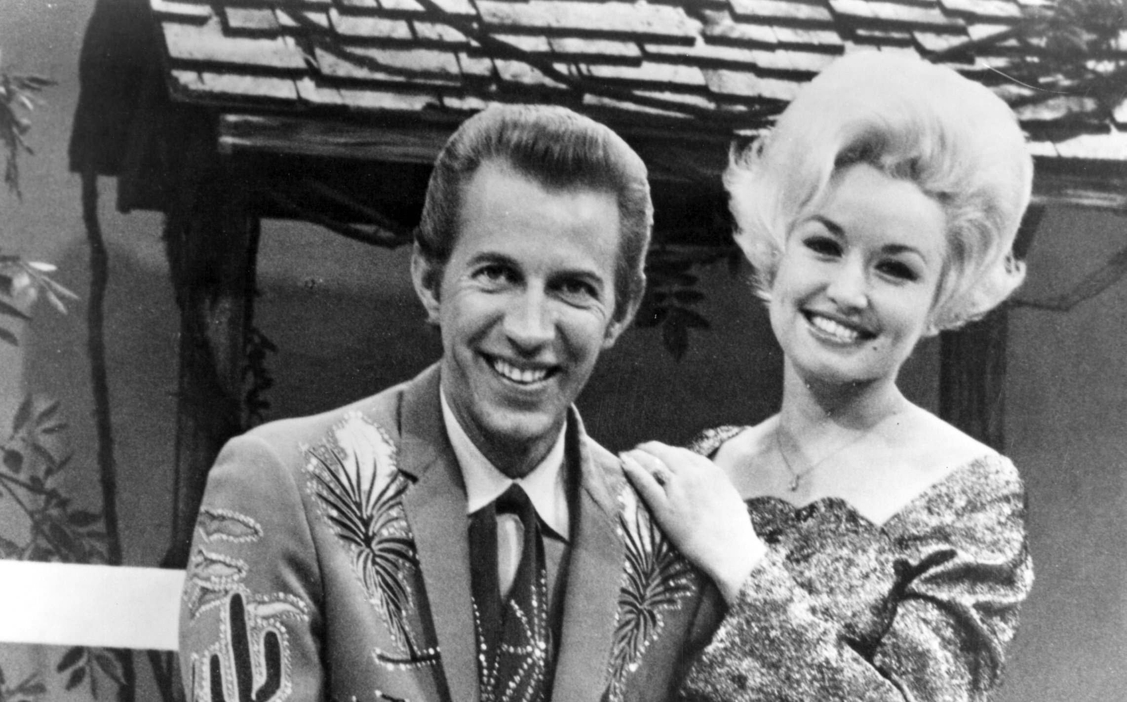 Country singer Dolly Parton with her collaborator Porter Wagoner on the set of his TV show in 1967. Mr. Wagoner is wearing a Nudie Suit designed by Nudie Cohn of Nudie's Rodeo Tailors.