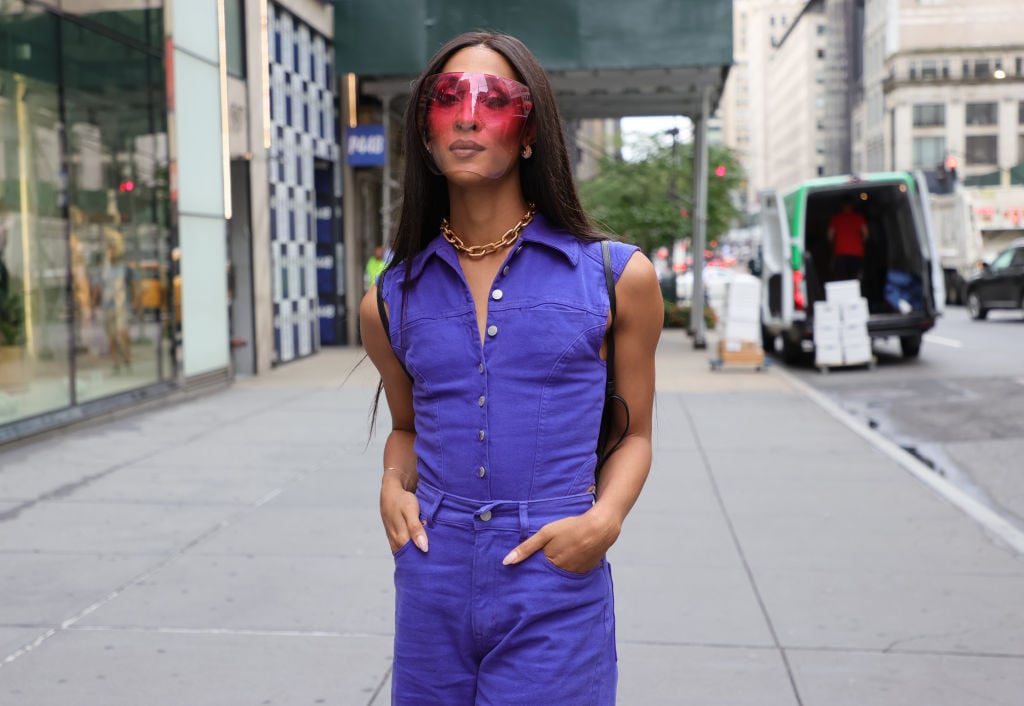 'Pose' star Mj Rodriguez poses in a purple jumpsuit and pink sunglasses with her hands in her pockets.