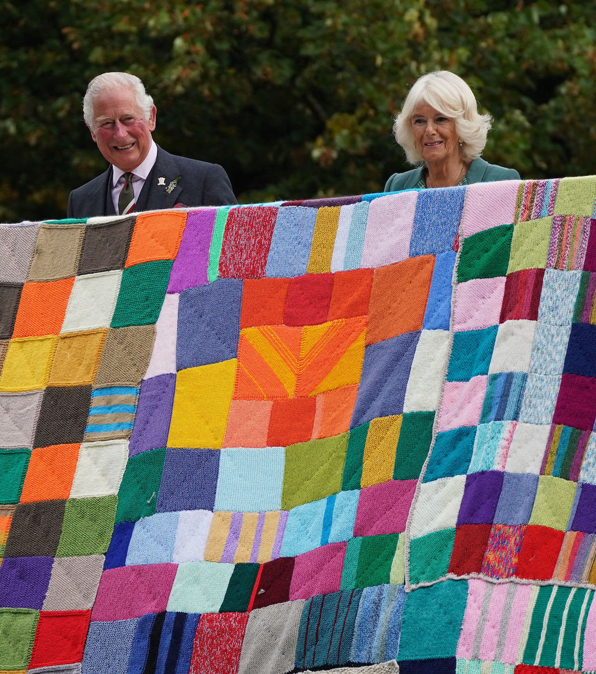 Prince Charles and Camilla Parker Bowles unfurl a multicolor patchwork quilt