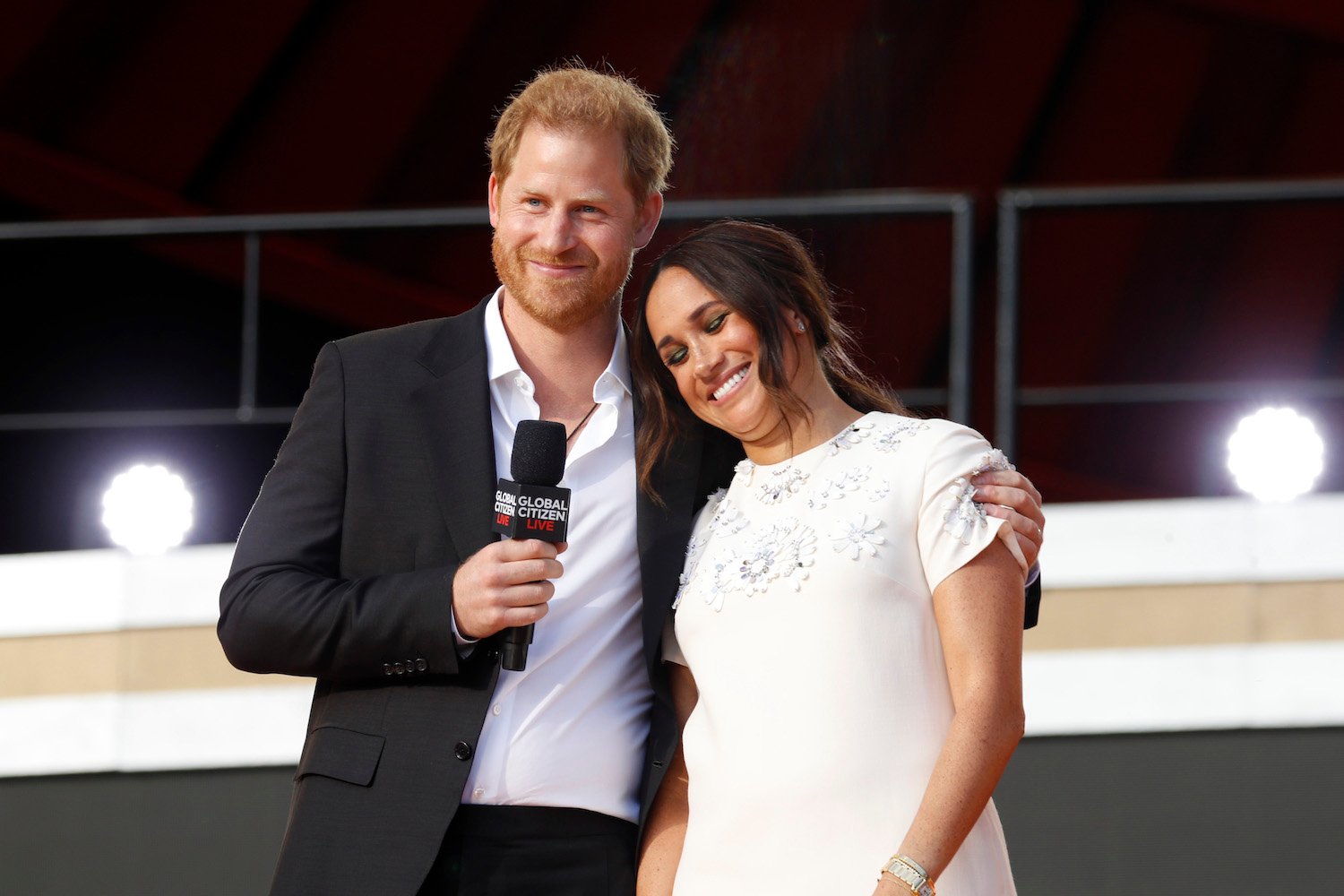 Prince Harry smiles with his arm around Meghan Markle onstage at Global Citizen Live