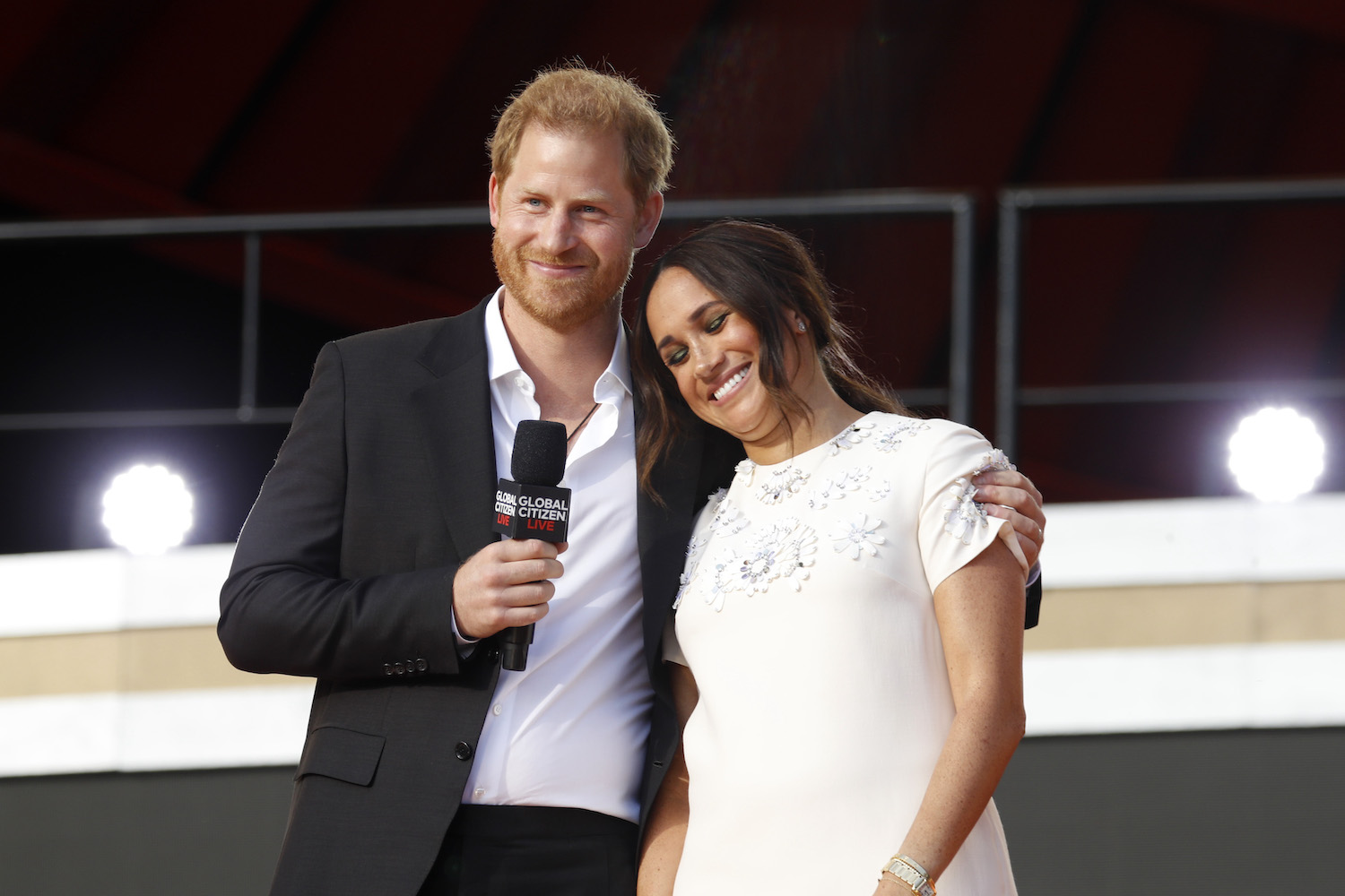 Prince Harry smiles with his arm around Meghan Markle onstage at Global Citizen Live