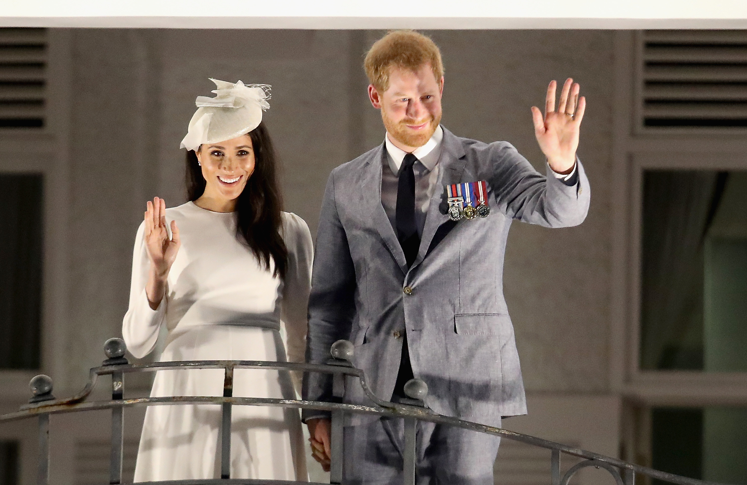 Prince Harry and Meghan Markle waving from the balcony of the Grand Pacific Hotel in Suva