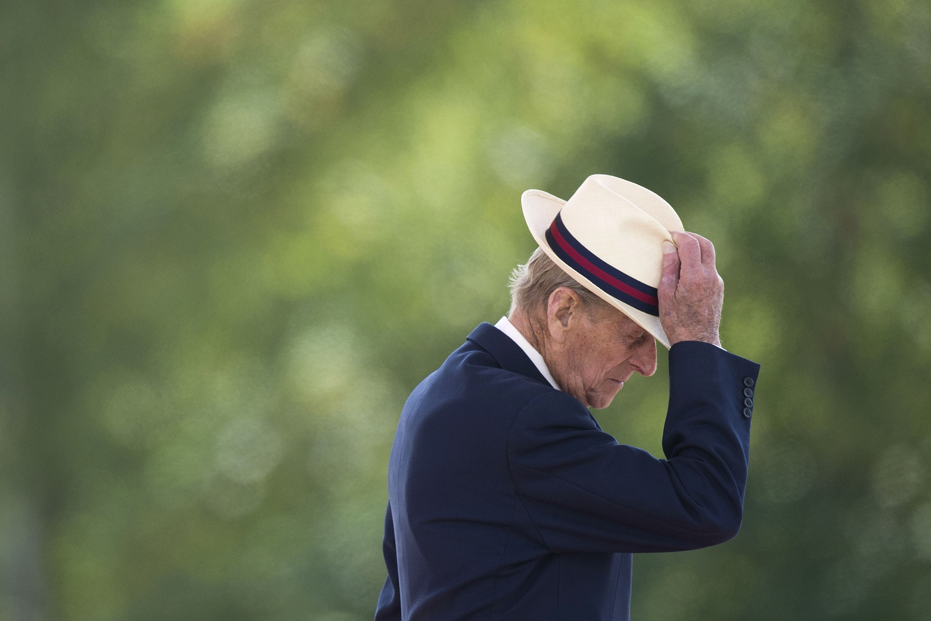 Prince Philip tugs the top of his hat after presenting medals in Fallingbostel, Germany